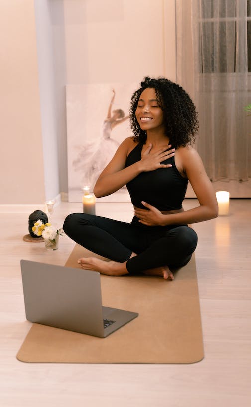 woman sitting with one hand on her chest and one on stomach, breathing slowly
